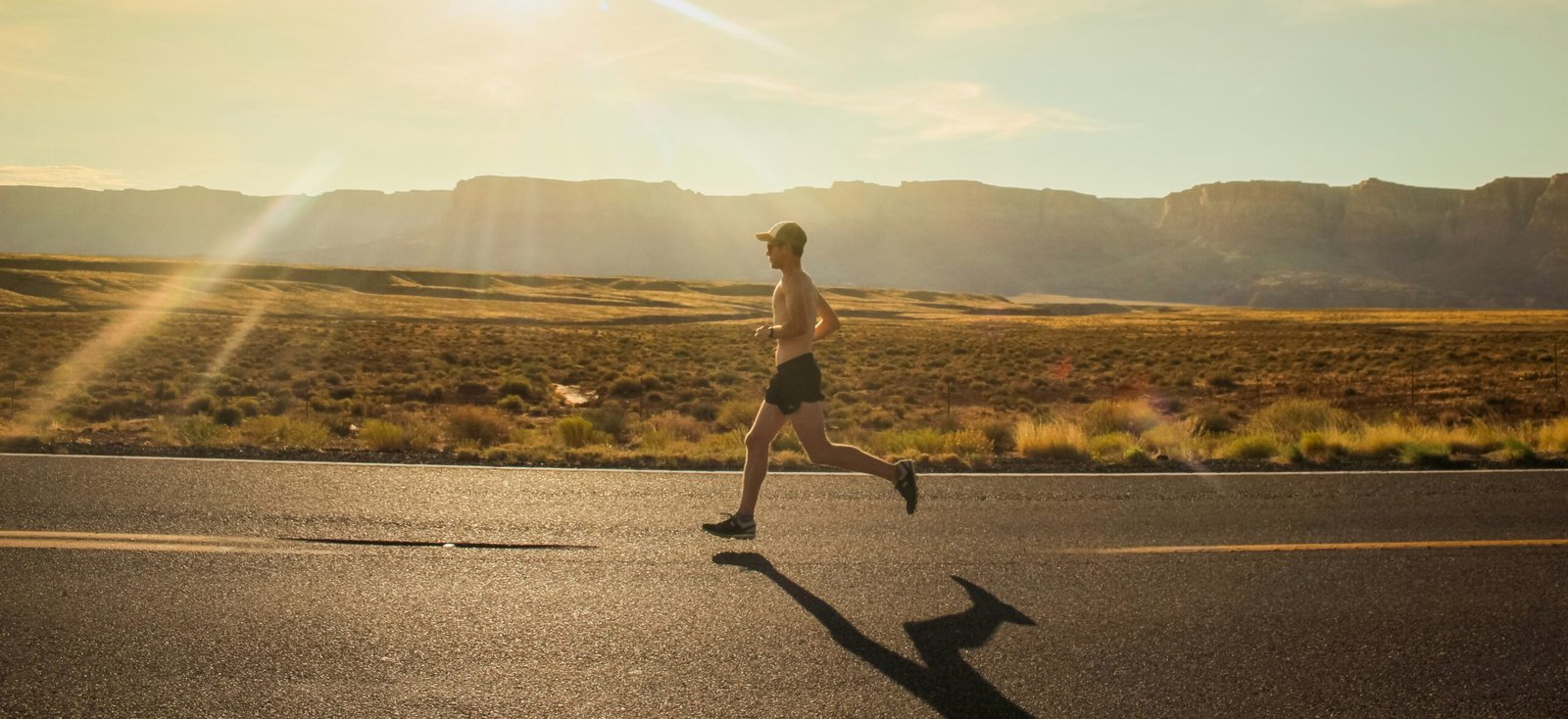 man in black shorts man in black shorts running on gray asphalt road during daytime